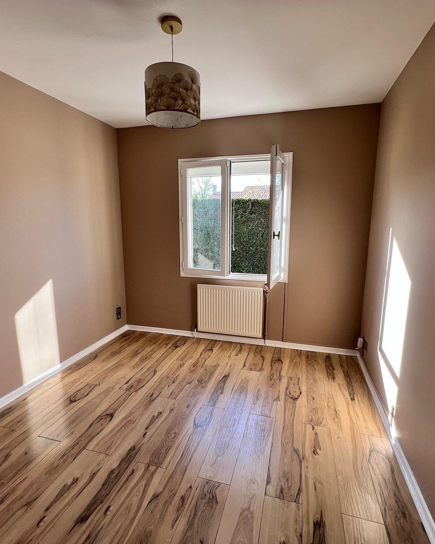 Décoration Salon Moderne : Canapé Blanc et Cuivre Géométrique Salon moderne et lumineux avec canapé blanc texturé, table d'appoint géométrique en cuivre, suspension filaire et vase avec branches sèches.